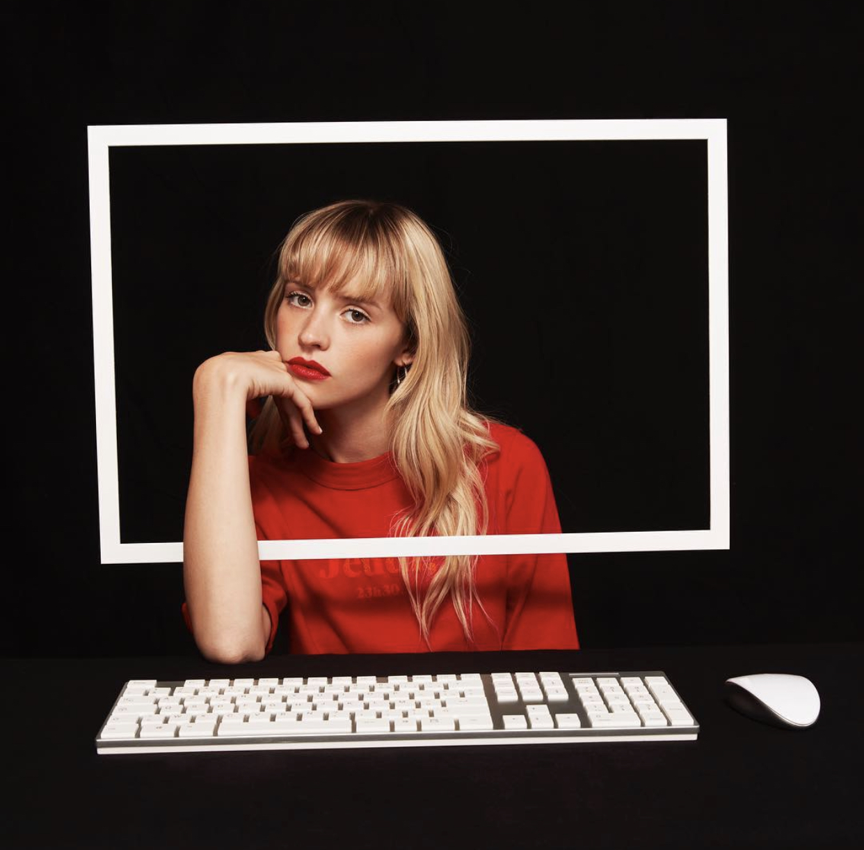 Portrait of Angele sitting behind a white frame and keyboard